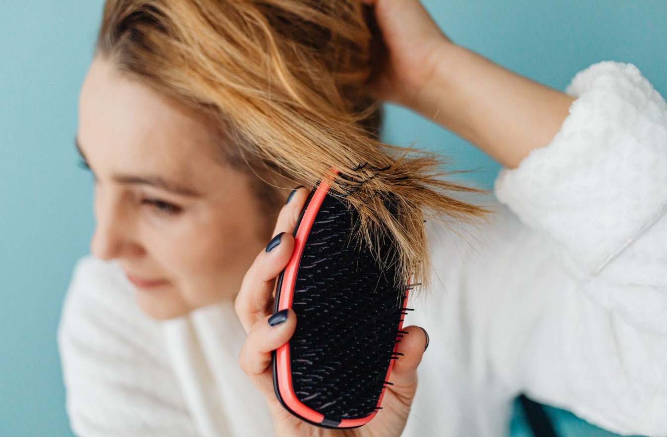 Woman brushing her hair — scalp eczema is a common condition often confused with dandruff