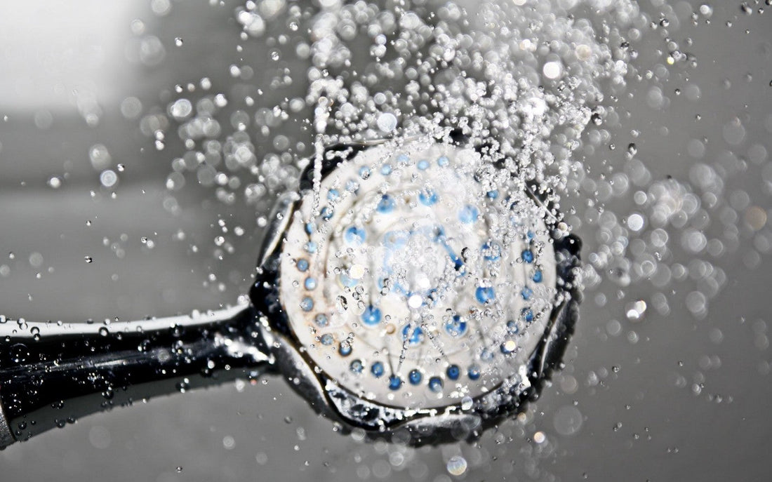Close-up of a shower head with water flowing — white vinegar is one of the best non-toxic methods for dissolving mineral scale